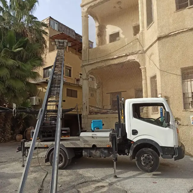 המנוף של מיה לגובה פרוס מול בניין ישן, משאית המנוף בחזית